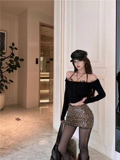 Woman in a leopard print skirt and black top posing indoors