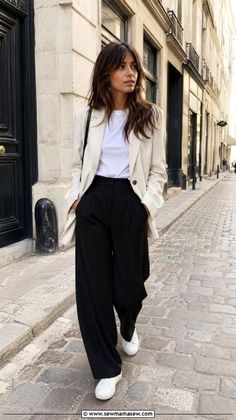 Woman in a blazer and wide leg pants walking on a cobblestone street