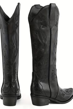 Pair of black cowboy boots with floral embroidery on a white background