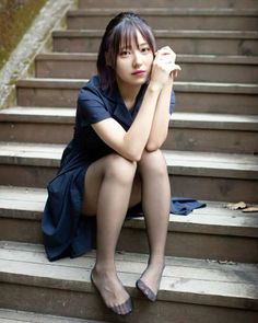 Woman in a dark blue dress and black tights sitting on wooden stairs