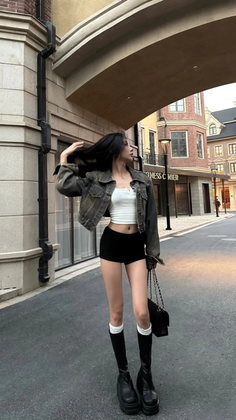 Woman in a crop top and shorts with a denim jacket on a street