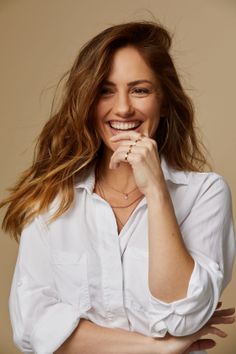 Woman with long hair and a white shirt smiling in a studio shot