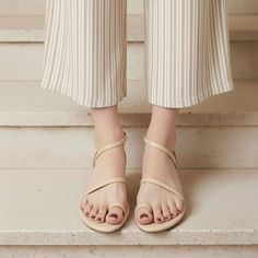 Person wearing striped pants and beige sandals with painted toenails on stairs