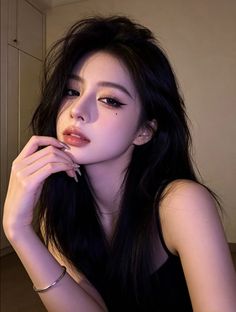 Woman with long black hair and dramatic makeup in a black top