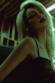 Woman with blonde hair and red lipstick in dramatic green lighting
