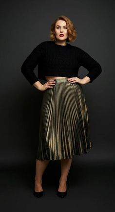 Woman with short hair and red lipstick wearing a cropped sweater and pleated skirt
