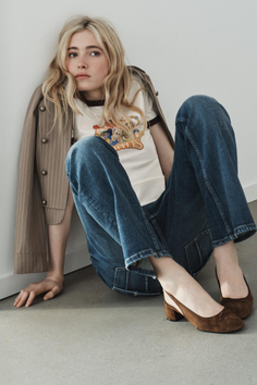 Woman with blonde hair sitting on the floor wearing a t-shirt and jeans