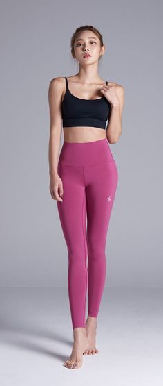 Woman in pink leggings and a black sports bra posing in a studio