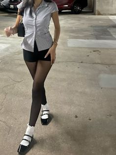 Person in a plaid shirt, black shorts, and tights with mary jane shoes