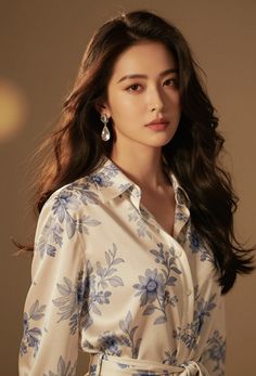 Woman with long dark hair wearing a floral print shirt and earrings