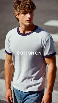 Man in a grey ringer t-shirt and blue jeans outdoors