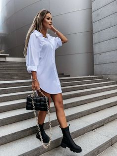 Woman in a white shirt dress and black boots walking down outdoor stairs