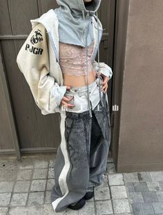 Person in a cropped hoodie, lace top, and baggy jeans outdoors