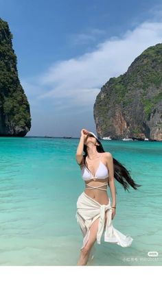 Woman in a white bikini and sarong on a tropical beach with clear water