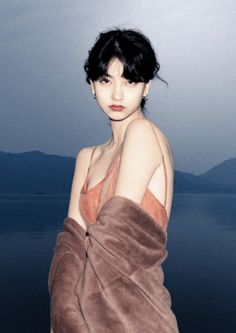 Woman with short dark hair wearing a fur coat over a spaghetti strap top outdoors