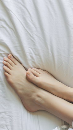 Bare feet on white sheets with soft lighting