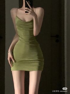 Person in a tight green dress taking a mirror selfie indoors