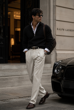 Man in a black sweater and beige pants walking on a city street