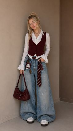 Blonde woman in a white shirt, red vest, and wide leg jeans holding a red handbag