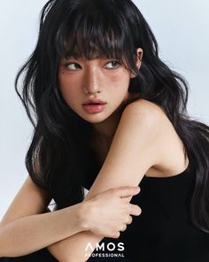 Woman with long black hair and freckles wearing a black top, looking to the side