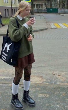 Young woman with blonde hair in a green sweater and brown skirt on a street