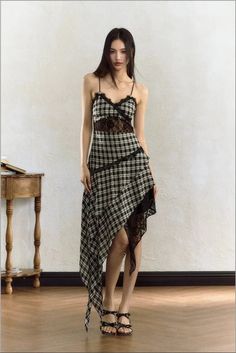 Woman in a plaid dress with lace trim and an asymmetrical hem standing indoors