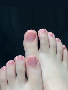 Close up of feet with pink nail polish against a dark background