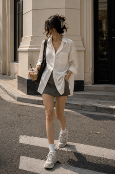 Woman in an oversized white shirt and mini skirt walking on a street