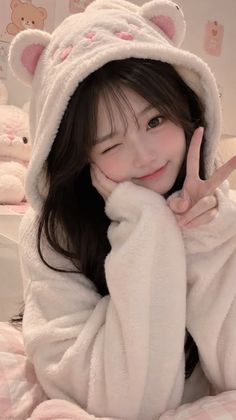 Woman in a white bear hoodie winking and making a peace sign