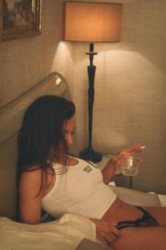 Woman in a white tank top and lace underwear lying on a bed