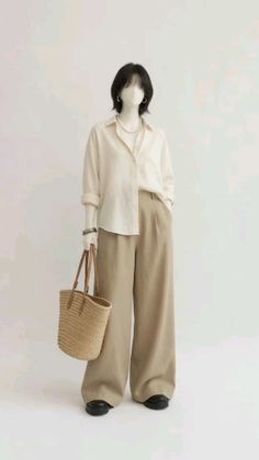 Mannequin wearing a white shirt, wide leg pants, and holding a straw bag