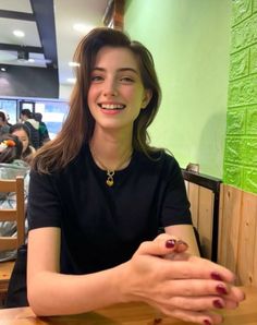 Woman with long hair and a gold necklace smiling in an indoor setting