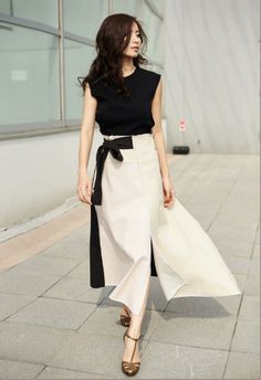 Woman with long hair wearing a black top and a two-tone wrap skirt outdoors
