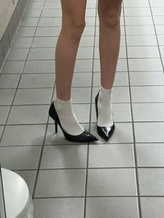 Person wearing black heels and white socks on a tiled floor
