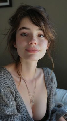 Woman with freckles and messy brown hair wearing a knitted sweater and necklace