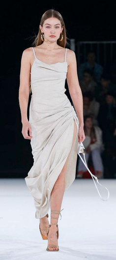Woman in a light-colored strappy dress with a high slit on a runway