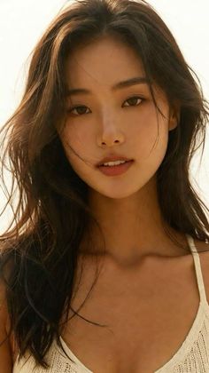 Woman with long brown hair and a white top in soft natural light