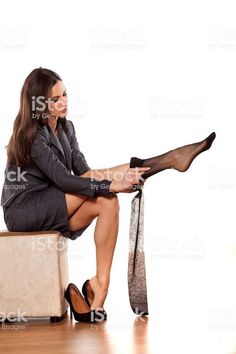 Woman in a business suit putting on black stockings while sitting