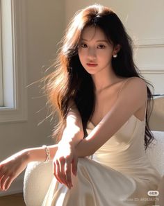 Woman with long hair in a white dress with pearl earrings, bathed in soft light
