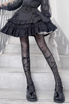 Person in a black ruffled dress and patterned tights with a plush toy on stairs