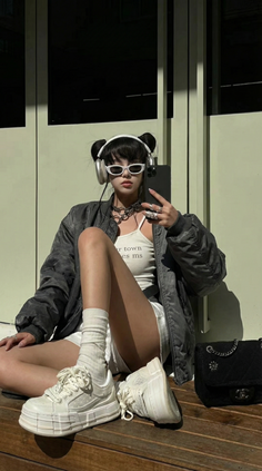 Woman with buns hair, sunglasses, and headphones sitting outdoors