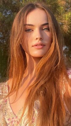 Woman with long hair and green eyes in a floral dress during golden hour