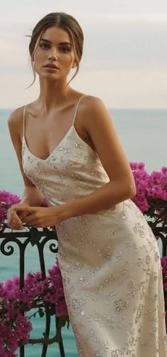 Woman in an elegant dress leaning on a balcony with an ocean view