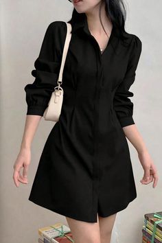 Woman in a black long-sleeve dress with a white shoulder bag