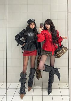 Two women in stylish outfits posing for a mirror selfie indoors