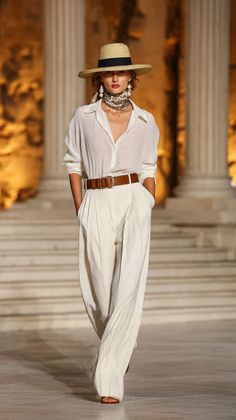 Woman in a straw hat and white outfit walking on a runway