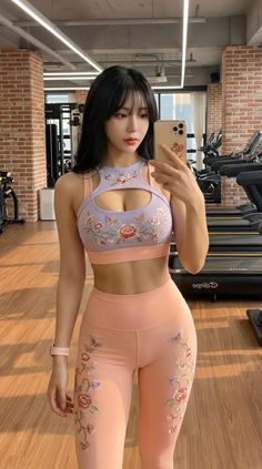 Woman in a floral sports bra and leggings taking a selfie in a gym