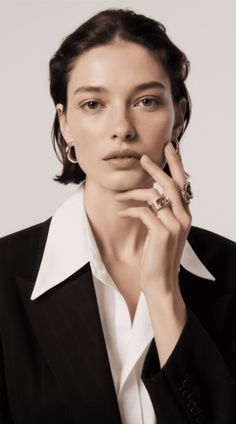 Woman with short hair wearing a suit and white shirt, touching her chin