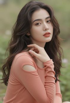 Woman with long dark hair and orange lipstick wearing a cut-out top outdoors