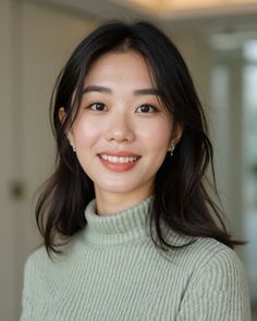 Woman with long dark hair wearing a light green turtleneck sweater, smiling